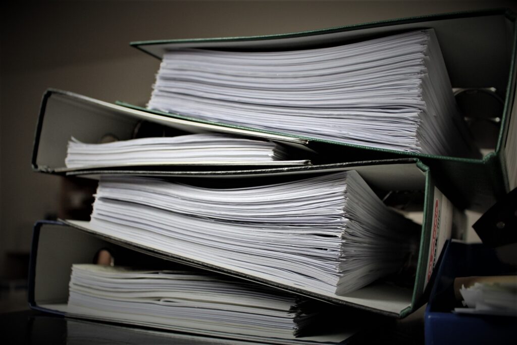 Documentos ordenados en carpetas que representan las diferencias entre testamento, herencia y sucesión
